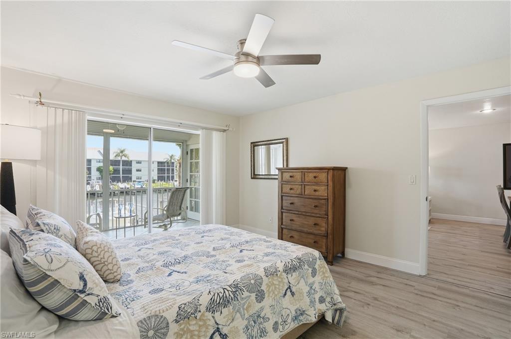 Bedroom featuring a water view, access to outside, light wood-type flooring, and ceiling fan