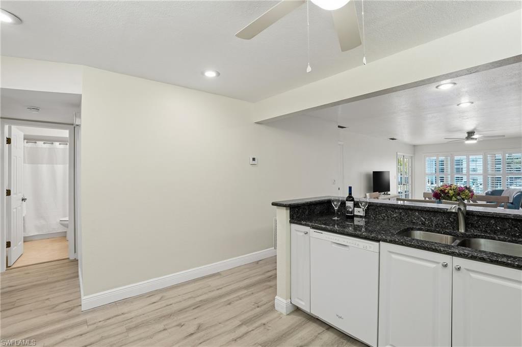 Kitchen featuring white cabinetry, ceiling fan, dark stone counters, dishwasher, and light LVP  flooring