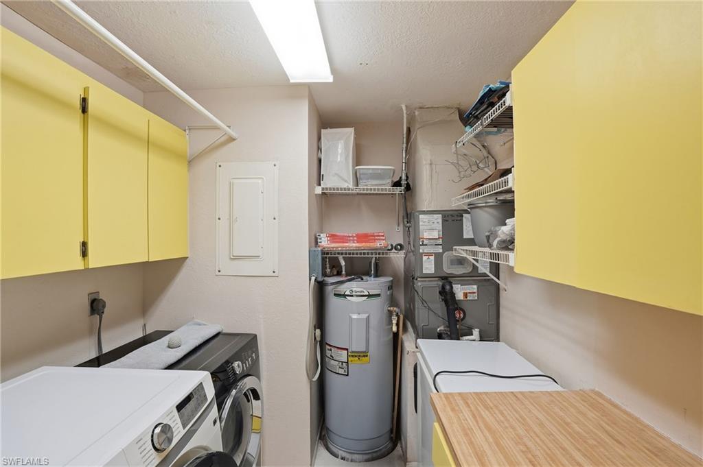 Laundry area featuring cabinet space, washing machine and dryer, electric panel, electric water heater, and heating unit