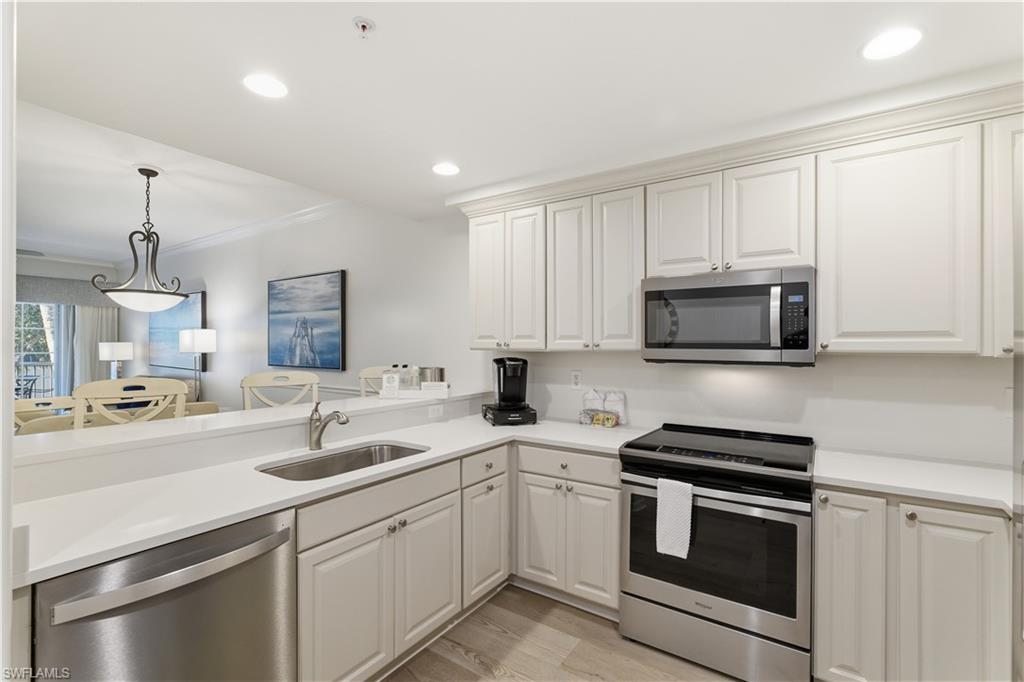 Kitchen featuring appliances with stainless steel finishes, hanging light fixtures, recessed lighting, crown molding, and light wood-style flooring