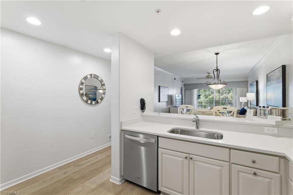 Kitchen featuring stainless steel dishwasher, light wood-type flooring, decorative light fixtures, open floor plan, and recessed lighting