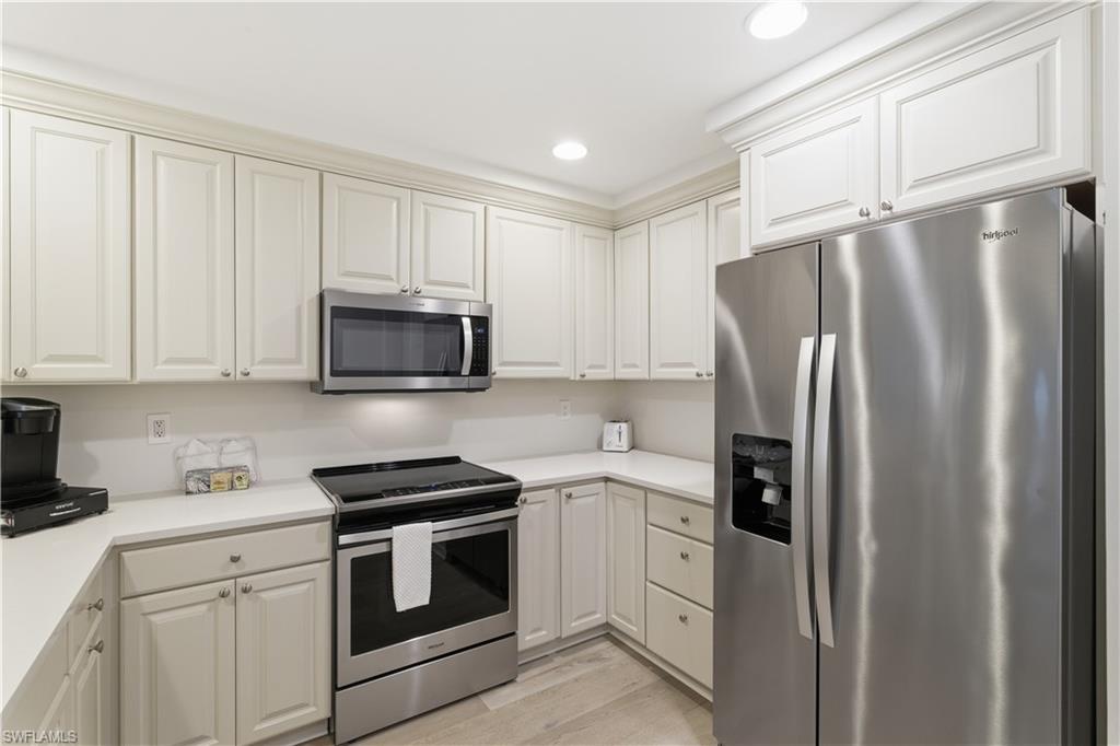 Kitchen with stainless steel appliances, light wood-style flooring, recessed lighting, and white cabinets