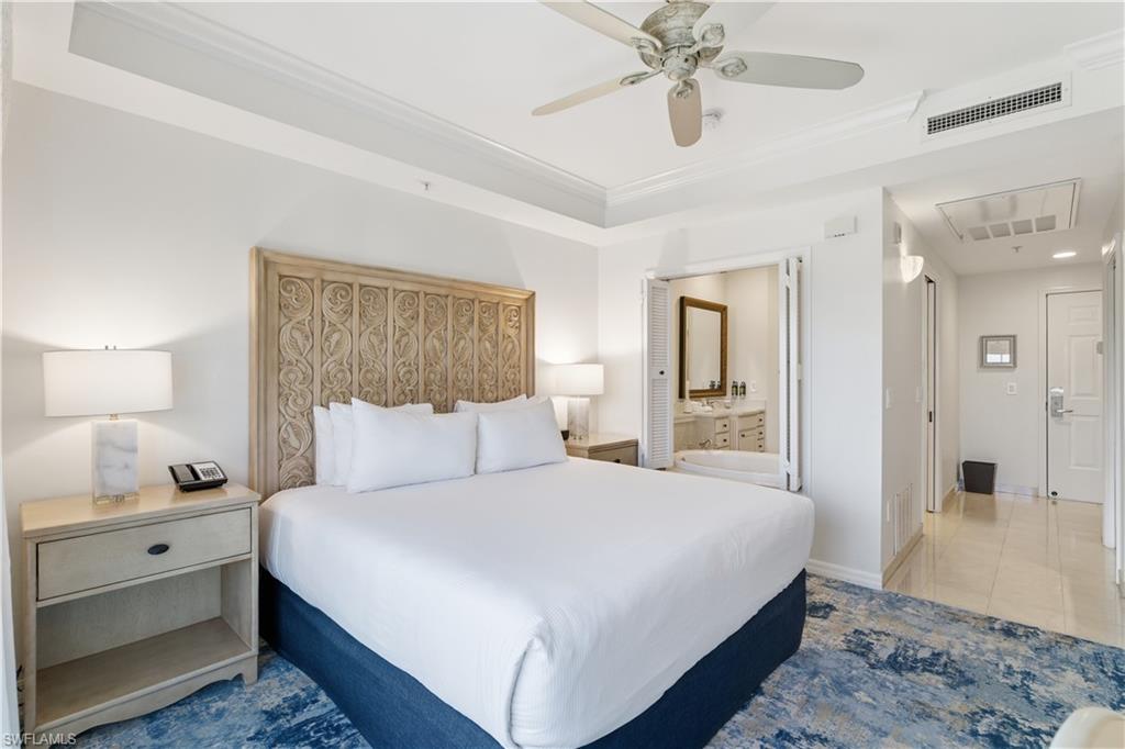 Bedroom with ensuite bath, a ceiling fan, crown molding, attic access, and light tile patterned floors