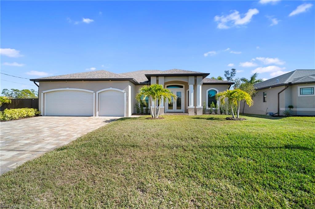 View of front of home with stucco siding, a front lawn, a garage, and decorative driveway