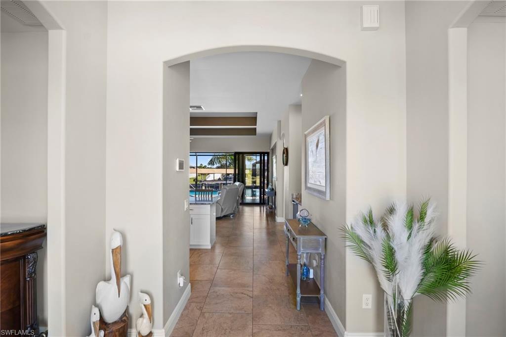 Corridor featuring arched walkways and light tile patterned floors