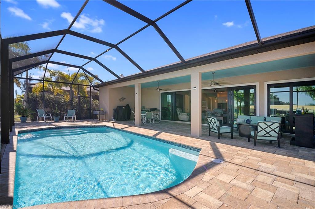 Outdoor pool with a sunroom, a patio, glass enclosure, and an outdoor hangout area