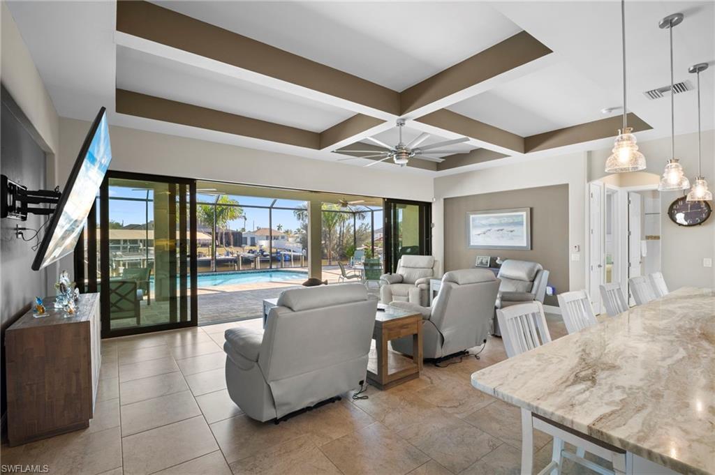 Living room with coffered ceiling, a ceiling fan, beam ceiling, and a sunroom