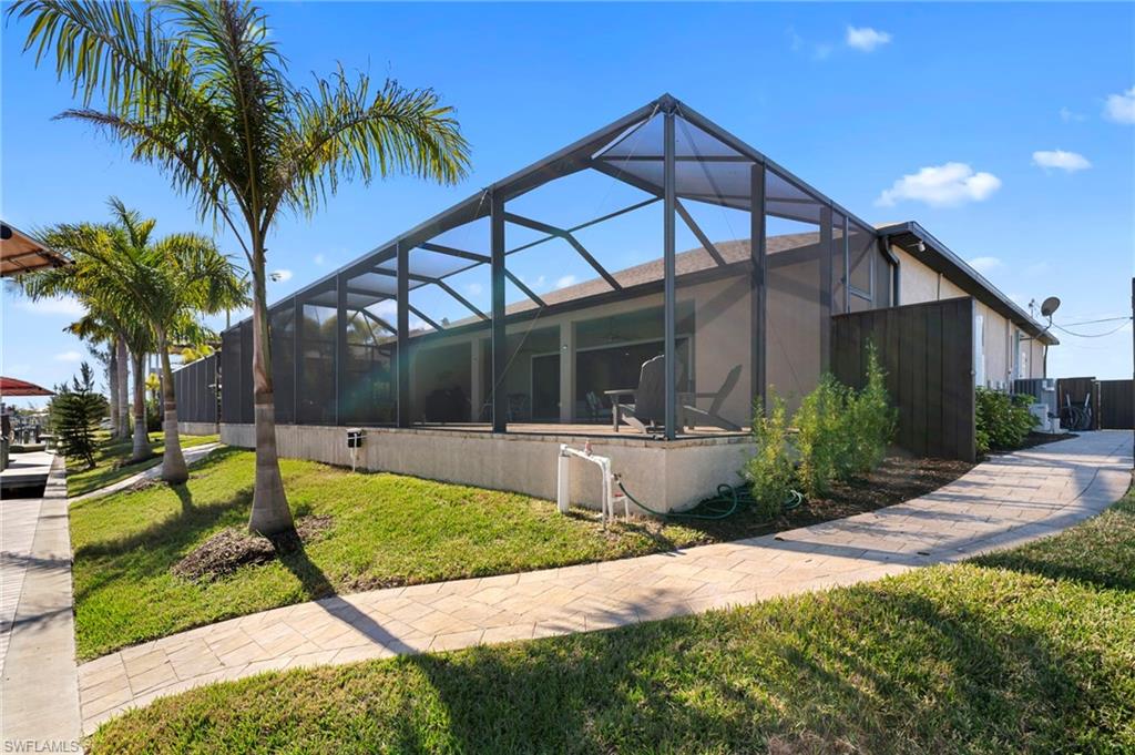 View of property exterior featuring a lanai, a lawn, and a sunroom
