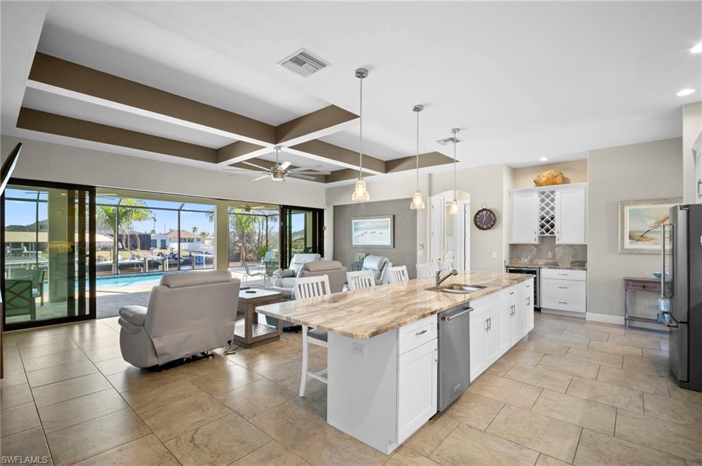 Kitchen with a breakfast bar area, white cabinetry, open floor plan, coffered ceiling, and appliances with stainless steel finishes