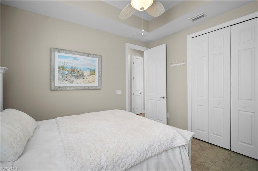 Bedroom with a closet, ceiling fan, and a tray ceiling