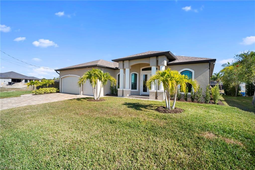 View of front of home with stucco siding, a front lawn, a garage, and decorative driveway