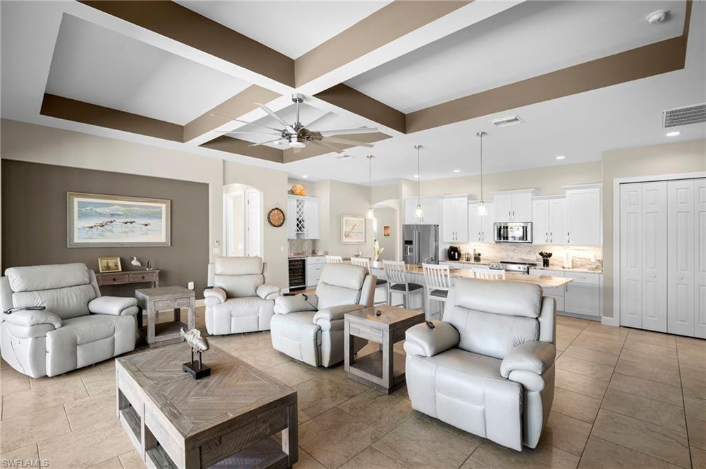 Living area featuring arched walkways, coffered ceiling, wine cooler, ceiling fan, and beam ceiling