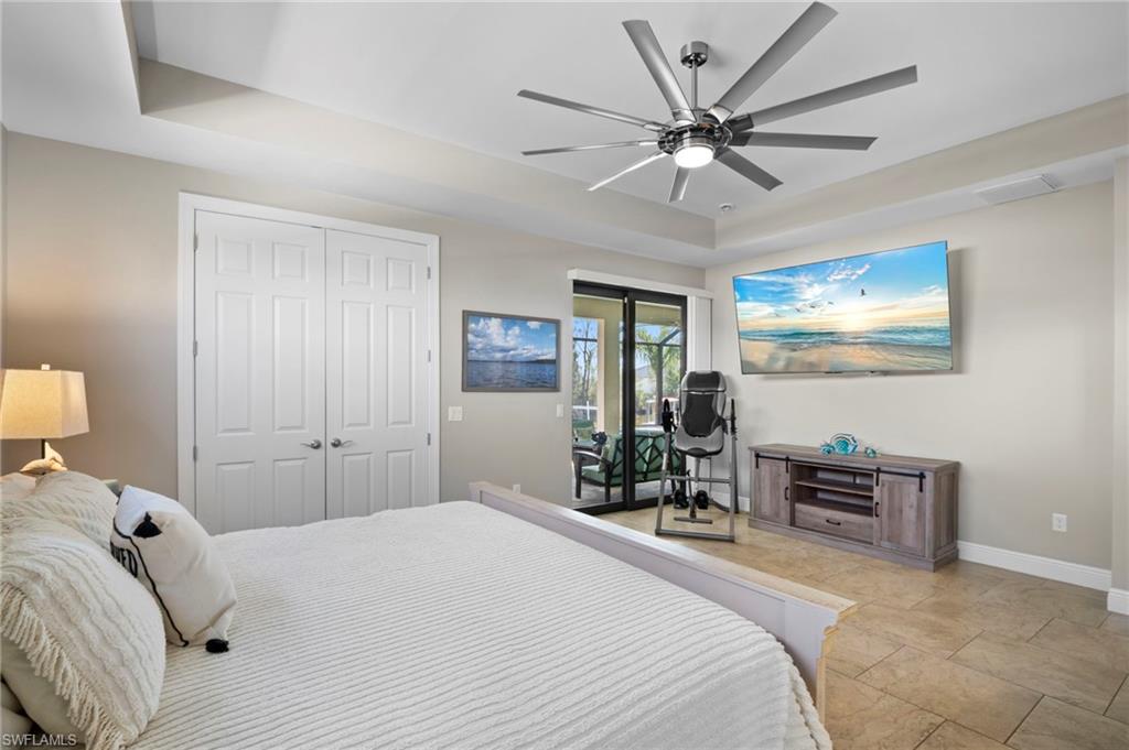 Bedroom featuring a raised ceiling, access to exterior, a ceiling fan, a closet, and an office area