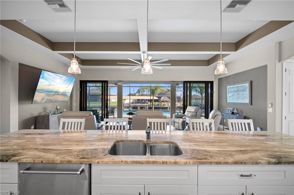 Kitchen with white cabinetry, a kitchen breakfast bar, light stone counters, decorative light fixtures, and open floor plan