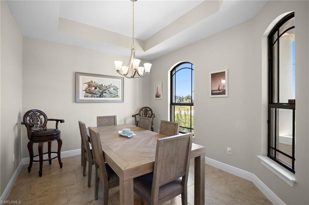 Dining space featuring a raised ceiling and a chandelier