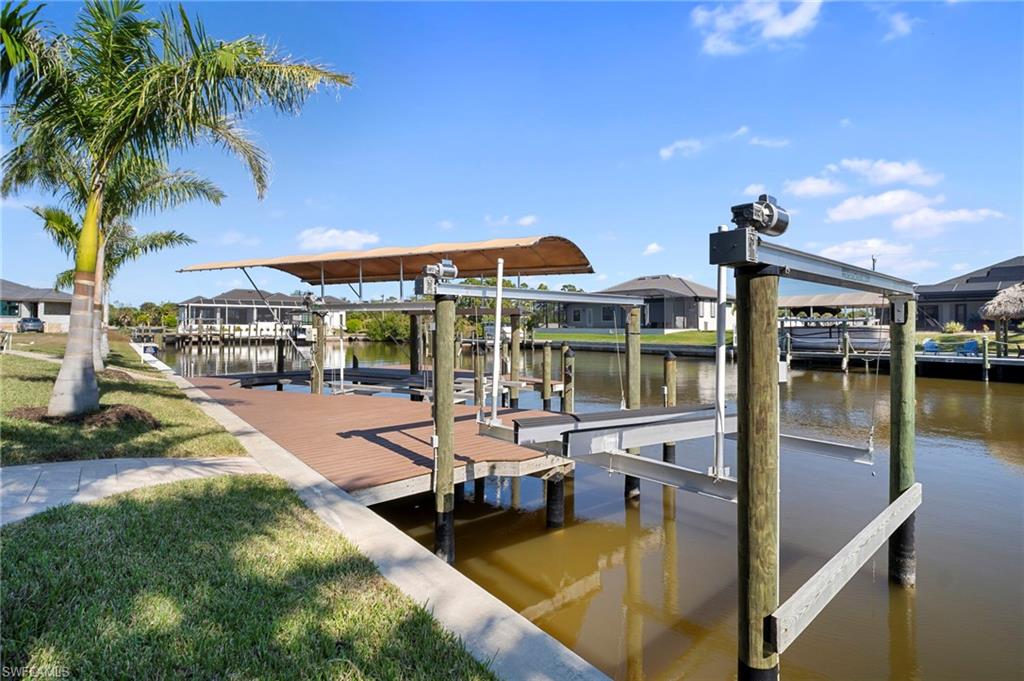 Dock area featuring boat lift, a water view, and a lawn