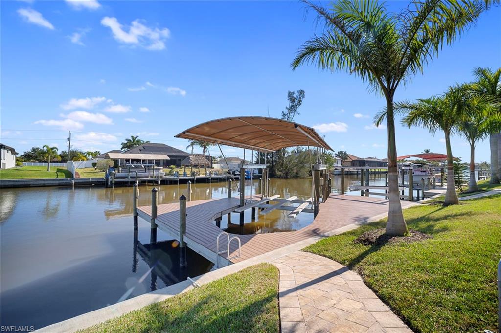 Dock featuring boat lift, a water view, and a lawn