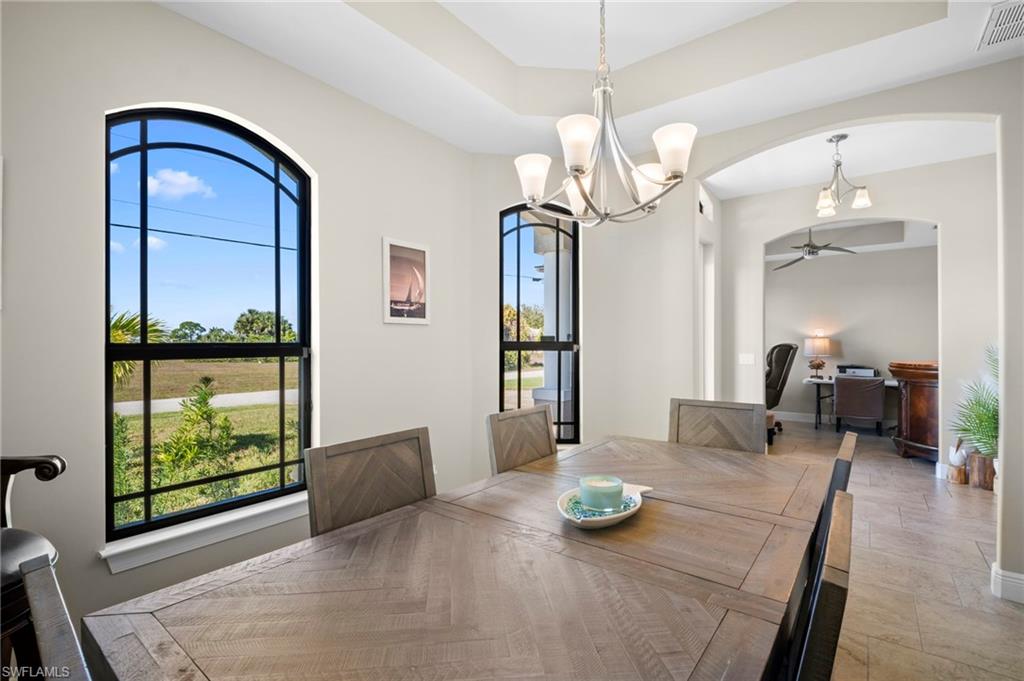 Dining space featuring a chandelier, ceiling fan, a raised ceiling, and arched walkways