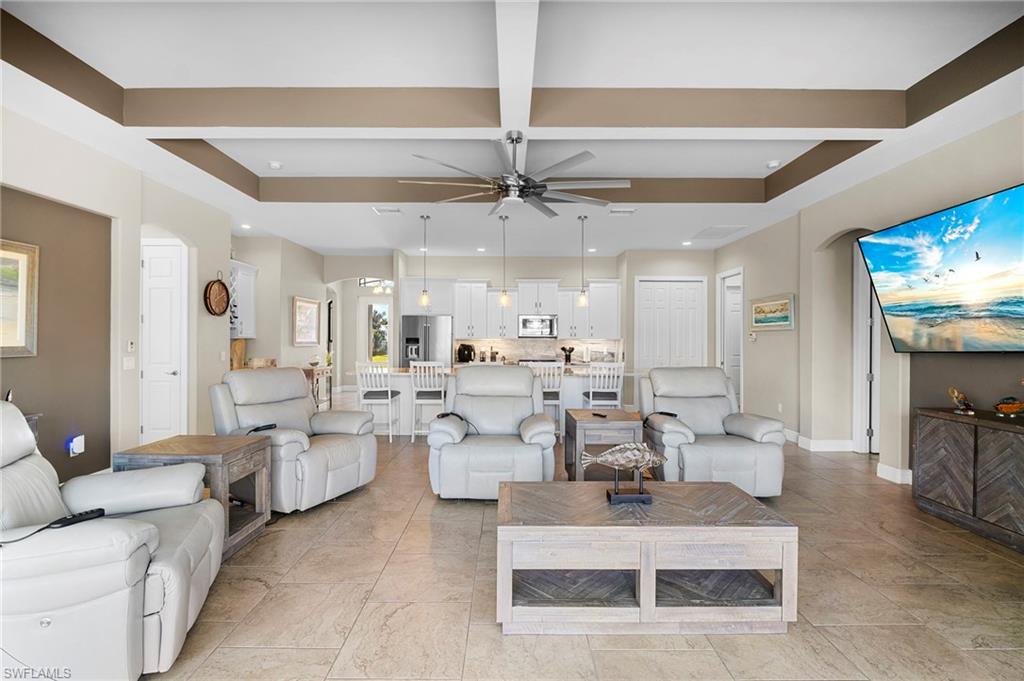 Living room with arched walkways, recessed lighting, a ceiling fan, and coffered ceiling