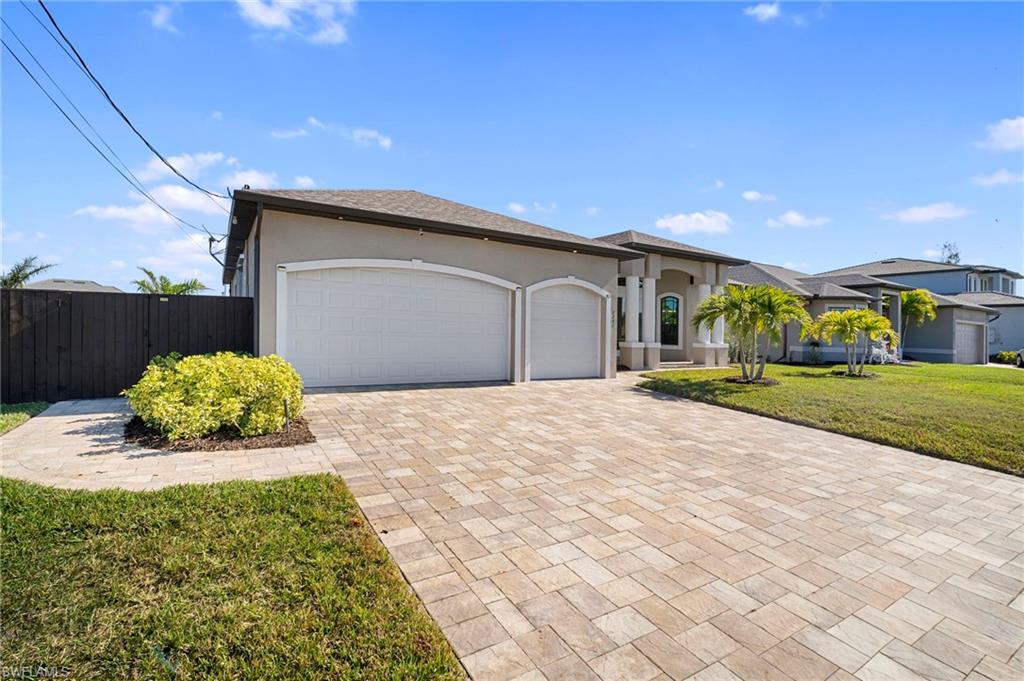 Ranch-style home with stucco siding, a garage, and decorative driveway