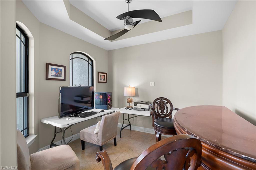 Office space with a tray ceiling and a ceiling fan
