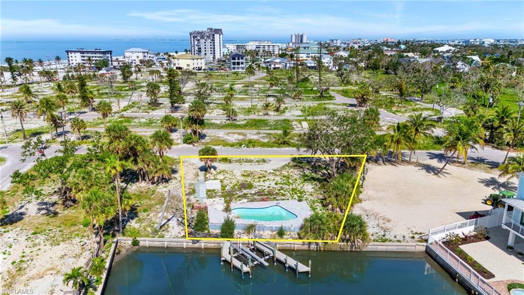 View of urban area with property boundaries highlighted, a pool area, and a large body of water - Virtually Edited Image
