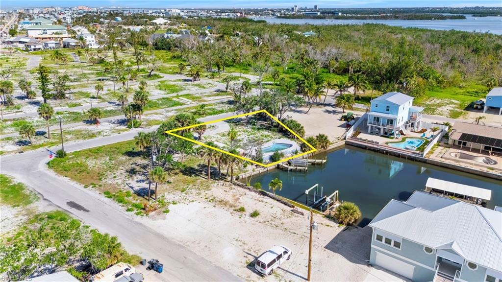 Aerial perspective of suburban area featuring a large body of water and property parcel outlined  - Virtually Edited Image