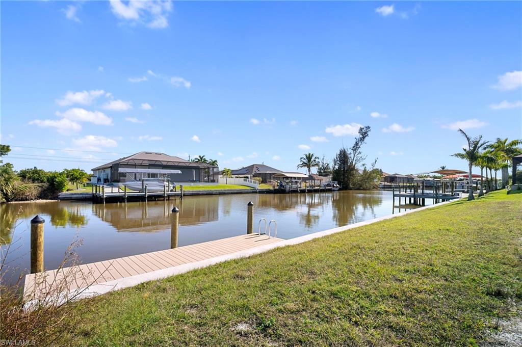 Dock area with a lawn, a water view, and a residential view