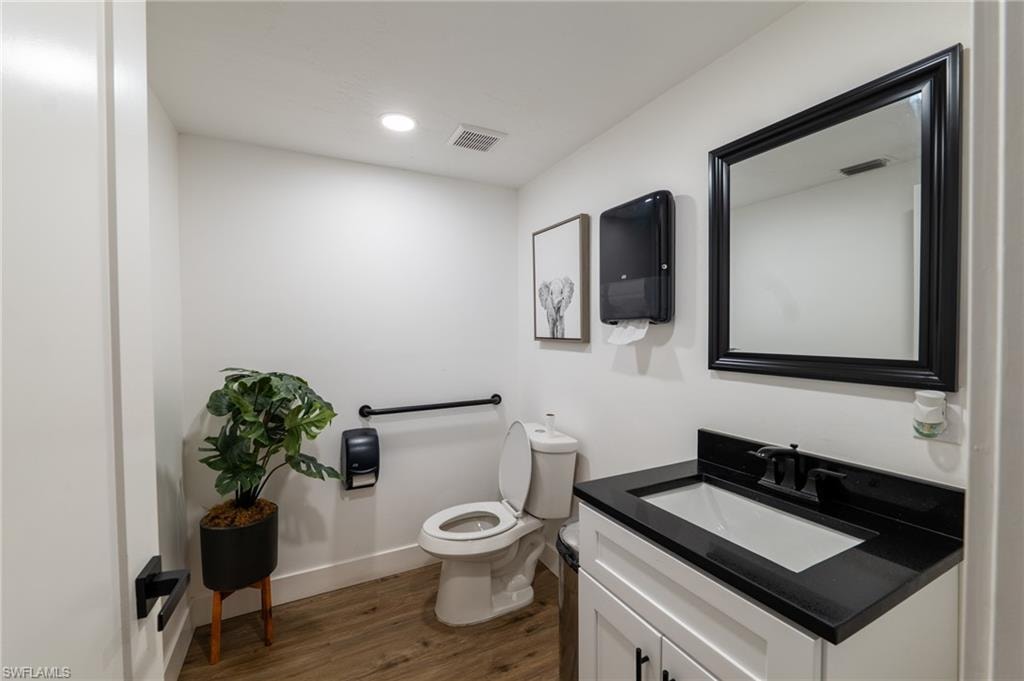 Half bathroom with vanity, dark wood-style floors, and recessed lighting