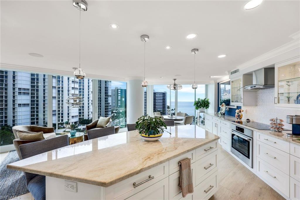 Kitchen featuring a center island, backsplash, oven, hanging light fixtures, and wall chimney exhaust hood