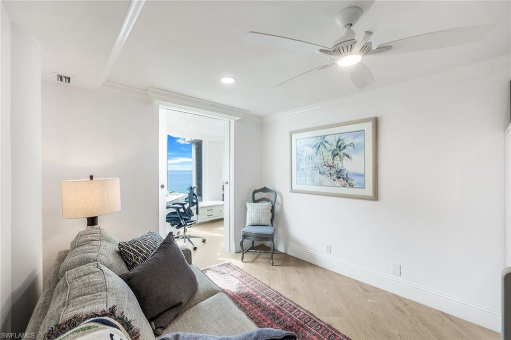 Living room featuring light wood-type flooring, ceiling fan, and ornamental molding