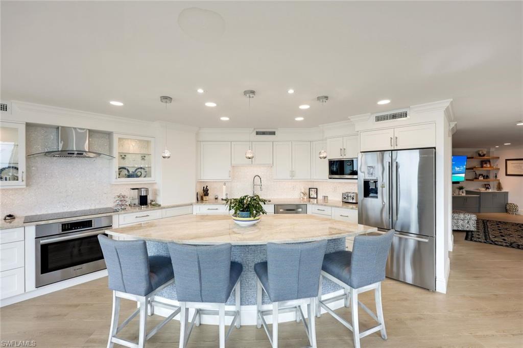 Kitchen with pendant lighting, wall chimney exhaust hood, a center island, and appliances with stainless steel finishes