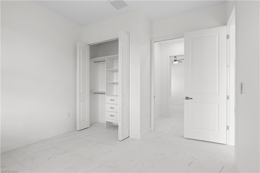Unfurnished bedroom with light marble finish flooring and a closet
