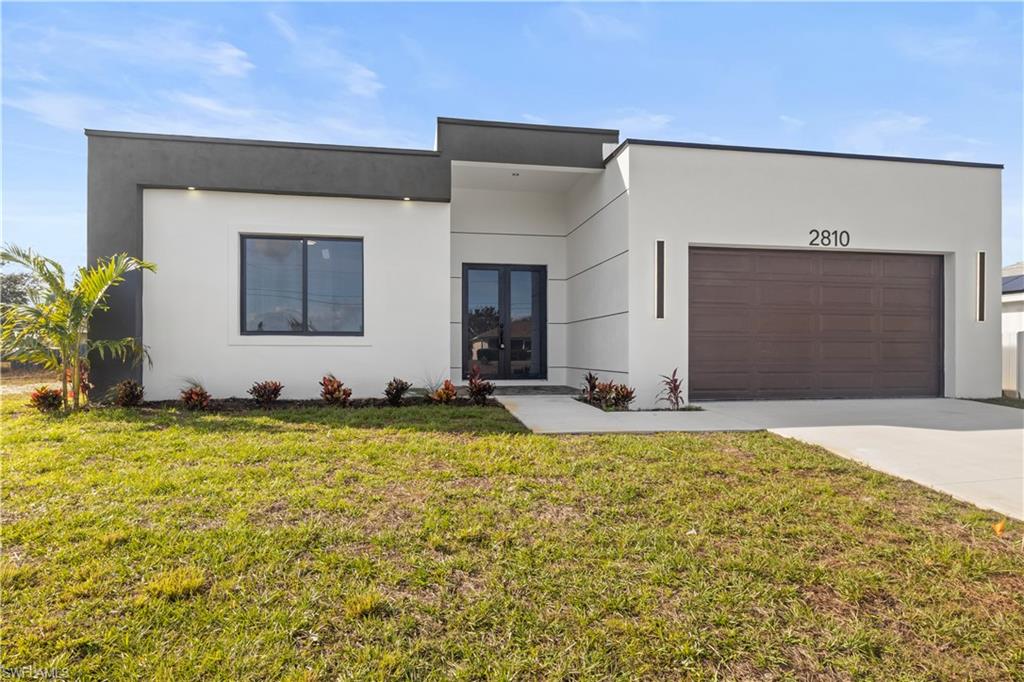 Modern home featuring a front lawn, stucco siding, driveway, and a garage