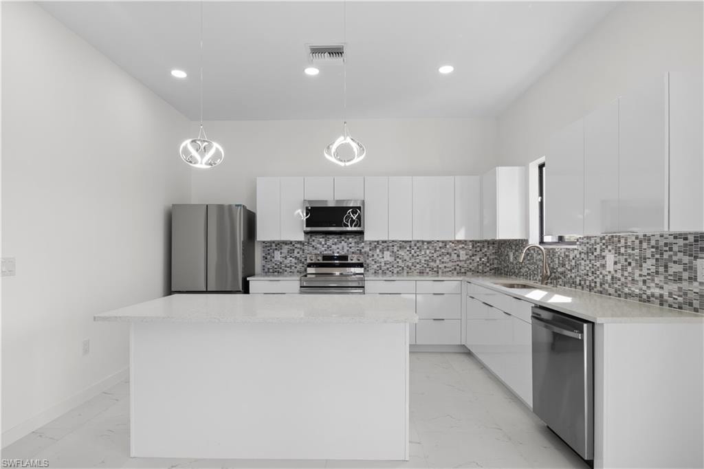 Kitchen with decorative light fixtures, light marble finish floors, appliances with stainless steel finishes, modern cabinets, and white cabinets
