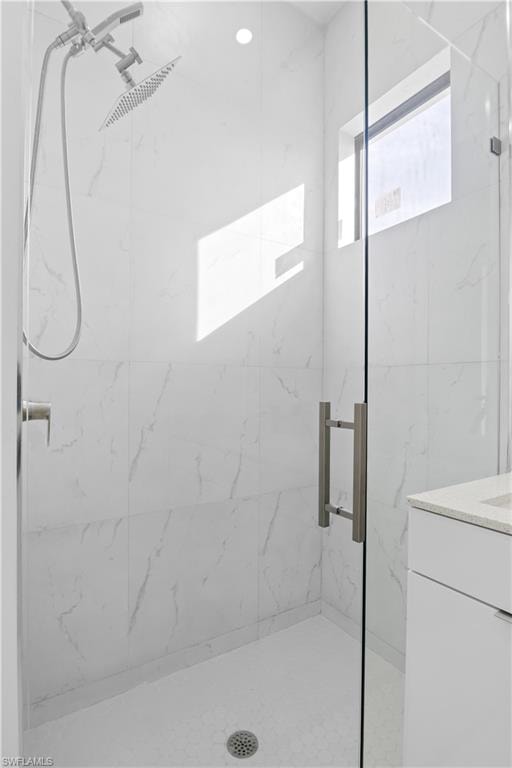 Full bathroom featuring a marble finish shower and vanity