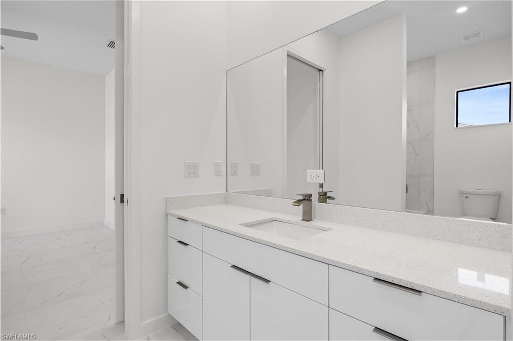 Full bath with light marble finish floors, vanity, and recessed lighting