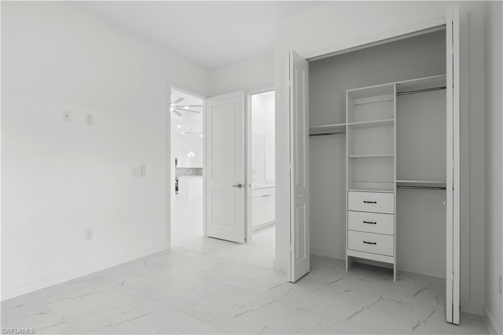 Unfurnished bedroom featuring light marble finish flooring and a closet