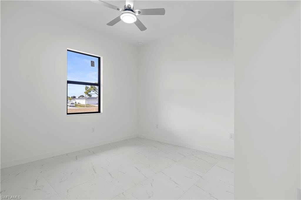 Unfurnished room featuring light marble finish flooring and a ceiling fan