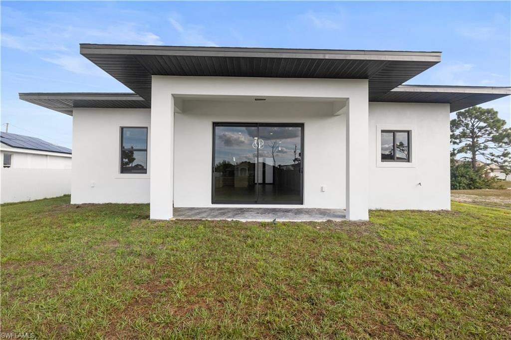 Back of property featuring stucco siding and a lawn
