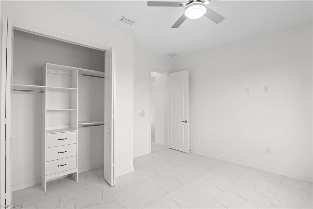 Unfurnished bedroom with light marble finish floors, a closet, and ceiling fan