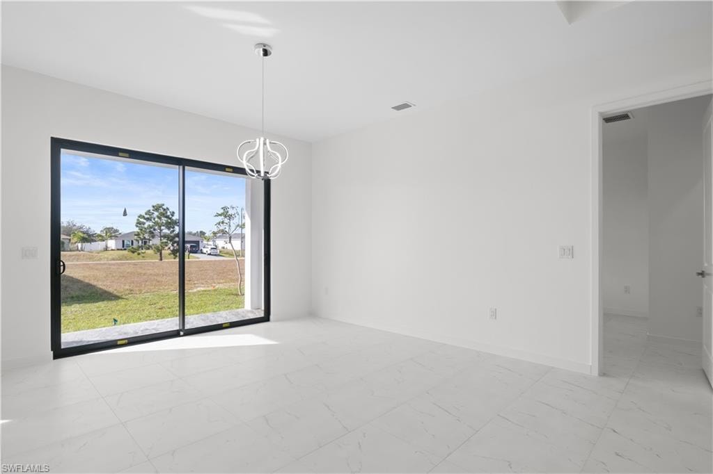 Unfurnished room featuring light marble finish floors and a chandelier