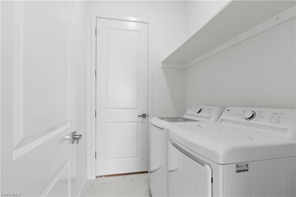 Laundry area with separate washer and dryer and light marble finish floors