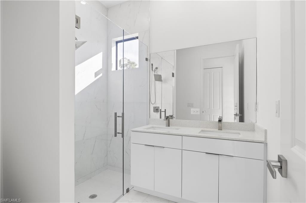 Bathroom with a marble finish shower and double vanity