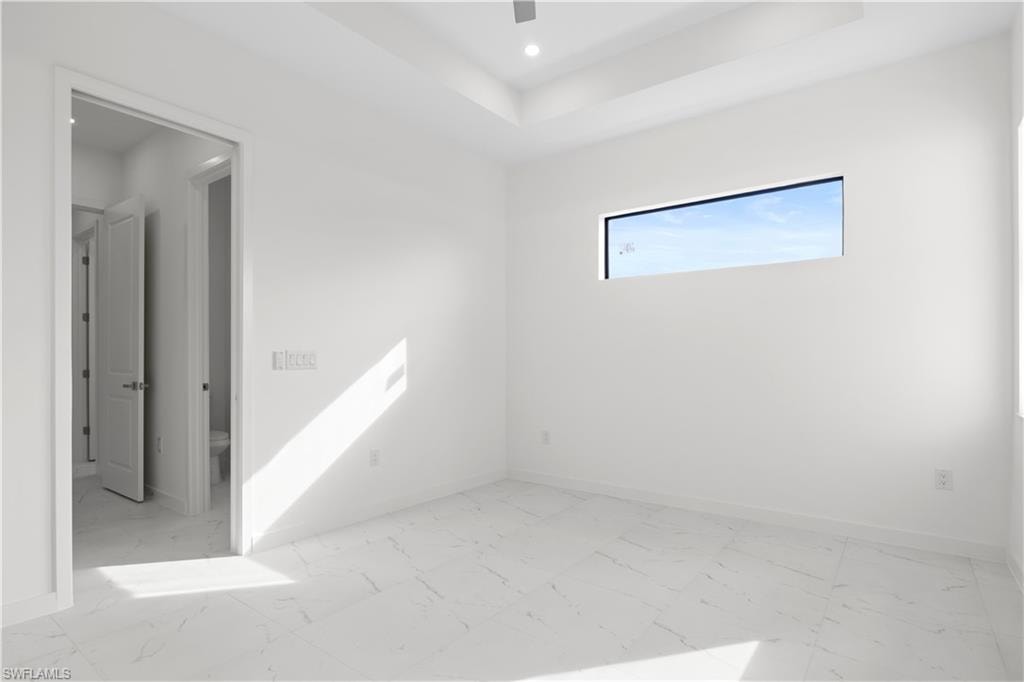 Spare room featuring light marble finish floors, recessed lighting, ceiling fan, and a tray ceiling