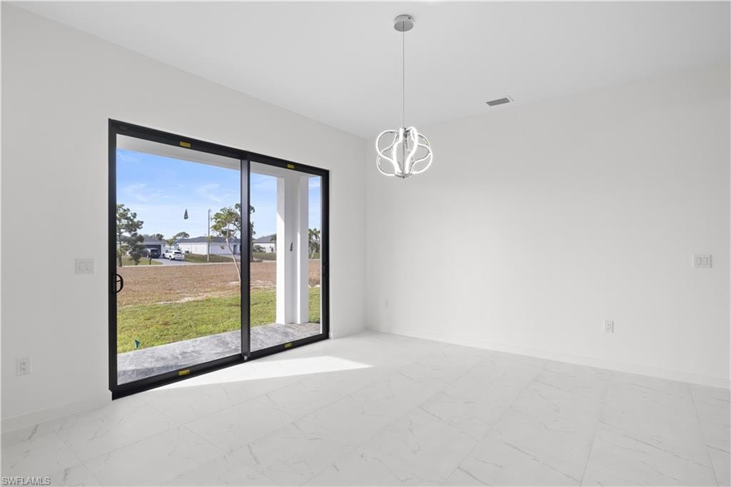 Empty room with light marble finish floors and a chandelier
