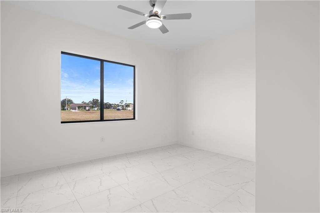 Empty room featuring light marble finish flooring and ceiling fan
