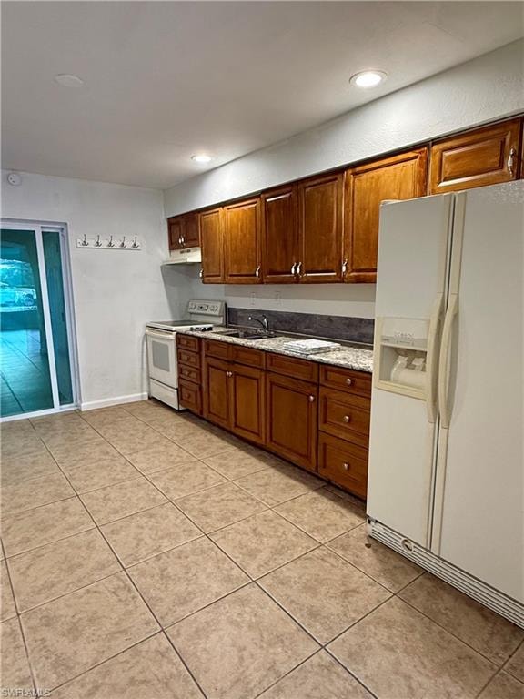 Kitchen with white appliances, recessed lighting, light tile patterned floors, brown cabinetry, and light stone counters