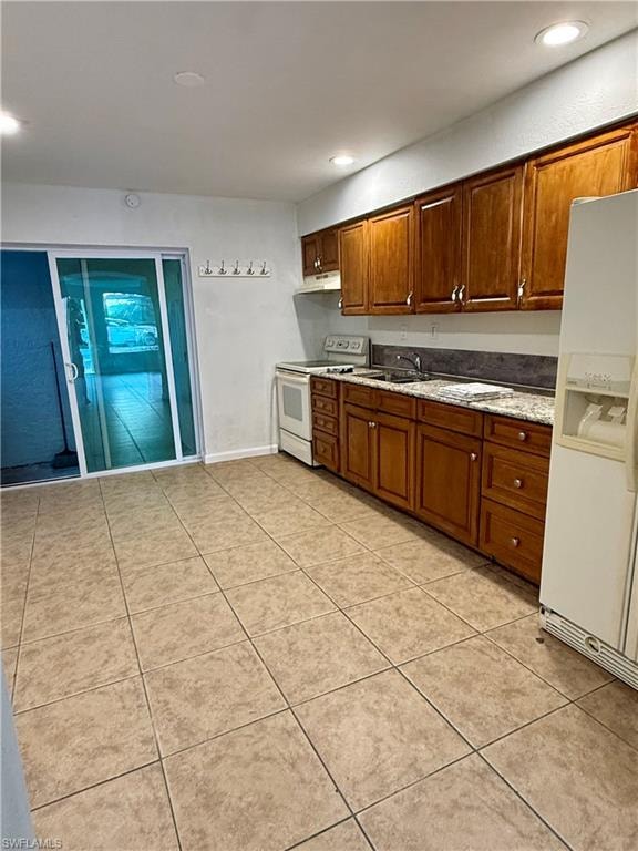 Kitchen with white appliances, brown cabinetry, recessed lighting, and light tile patterned flooring