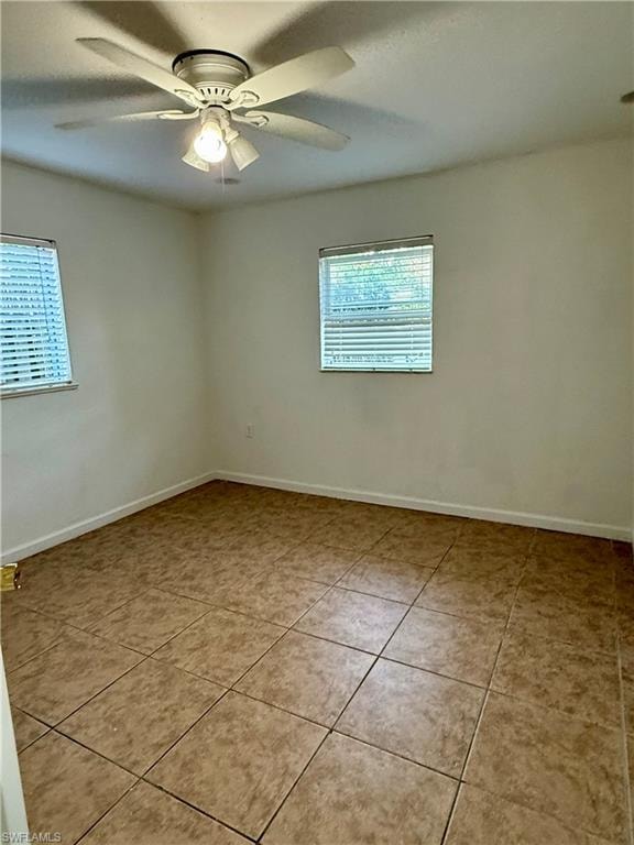 Empty room featuring plenty of natural light, light tile patterned floors, and a ceiling fan